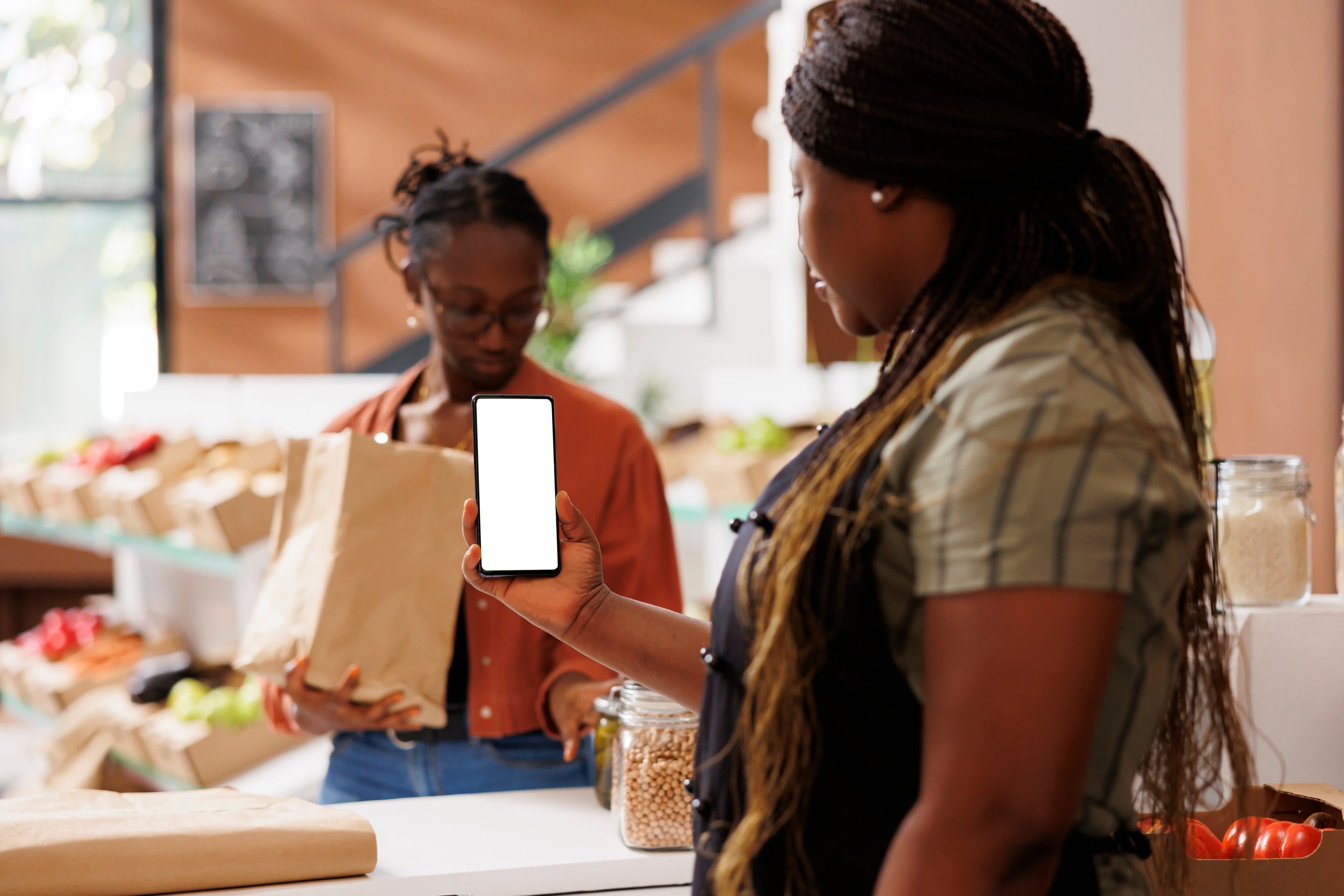 A shop worker holding out a phone at the counter