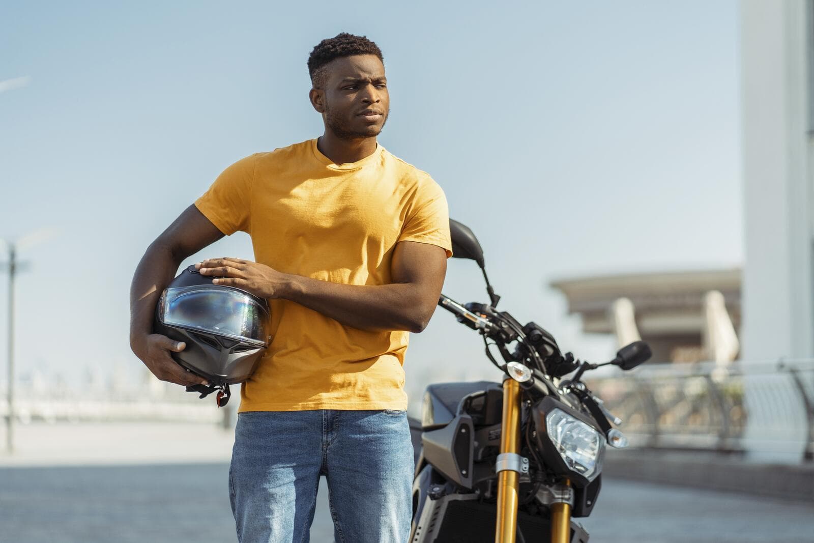 A rider holding his helmet beside his motorbike